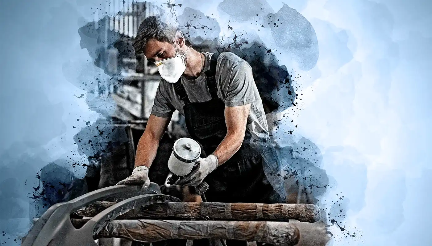 junger Fahrzeuglackierer bearbeiten Bauteil und trägt eien Atemmaske